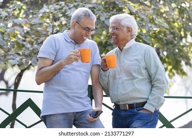 Two Old Male Friends Having Fun Raising A Toast With Coffee Cups At Park
