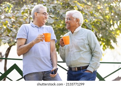 Two Old Male Friends Having Fun Raising A Toast With Coffee Cups At Park
