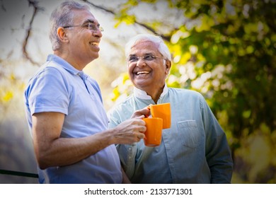 Two old male friends having fun raising a toast with coffee cups at park
