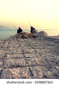 Two Old Men Sat For Fishing At The Edge Of The Corniche In Front Of The Sea At Sunset In Lebanon