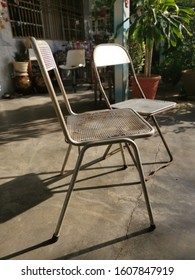 Two Old Metal Antique Chairs Left On The Lawn.