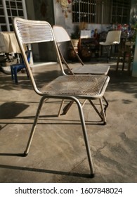 Two Old Metal Antique Chairs Left On The Lawn.