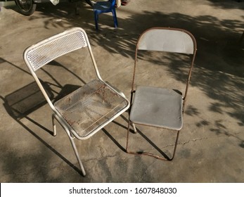 Two Old Metal Antique Chairs Left On The Lawn.