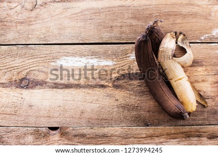 Two old ripe bananas on rustic wooden table, top view