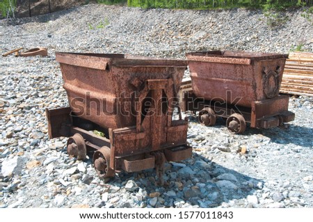 two old rusty minecarts on a background of stones