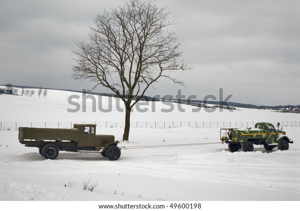 two old trucks in\
winter road. Car on a tow