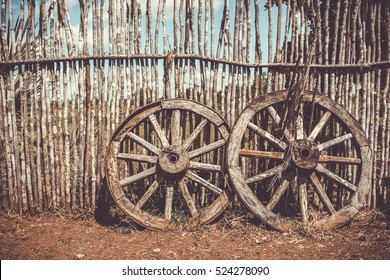 Two old wagon wheels near the wooden fence. Old cart wheel as a symbol and concept of fortune and fate, filtered with soft pastel colors with filters.
