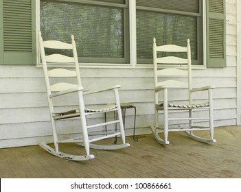 Two Old White Painted Wooden Rocking Chairs On A Front Porch