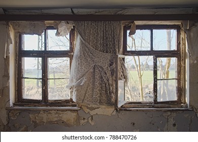 Two Old Windows With Tattered White Curtain In An Old Abandoned And Decayed Building Somewhere In Germany In Europe Overlooking A Field With Trees