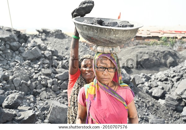 Two old woman working together and helping each\
other in coal mine