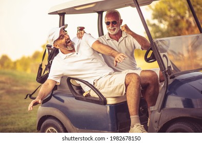 Two Older Friends Are Riding In A Golf Cart.