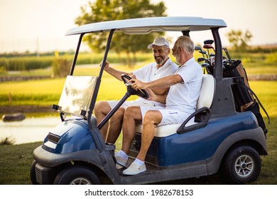 Two older friends are riding in a golf cart. - Shutterstock ID 1982678153