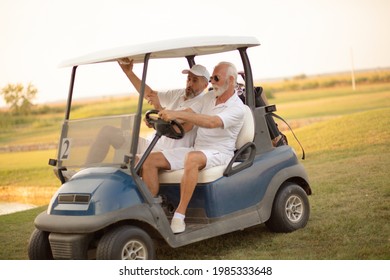 Two Older Friends Are Riding In A Golf Cart.