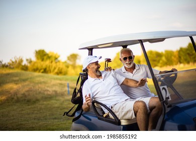 Two older friends are riding in a golf cart. - Shutterstock ID 1985855192