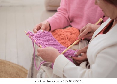 two older women knitting with natural wooden needles and environmentally friendly pink wool, demonstrating how knitting can be both a creative and sustainable hobby for people of all ages - Powered by Shutterstock