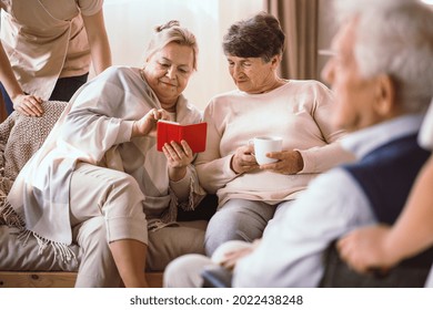 Two Older Women Looking At  The Picture On The Phone Together