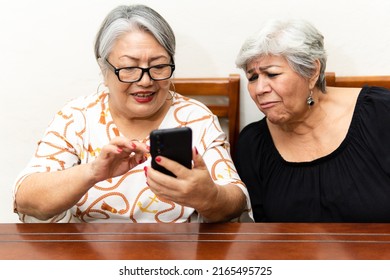 Two Older Women Watching News On Cell Phones, Making Faces At The Lack Of Glasses. 