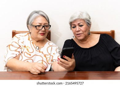 Two Older Women Watching News On Cell Phones, Making Faces At The Lack Of Glasses. 