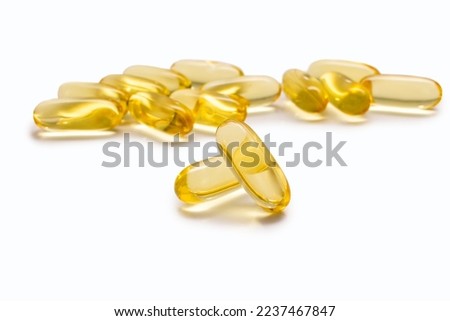 Two Omega 3 capsules isolated on a white background and many other capsules on a blurred background. Fish oil capsules close-up. The concept of healthy eating and healthy food supplements