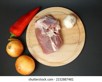 Two Onions, Pepper And Pork Fillet On A Cutting Board On A Black Background, View From Above