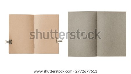Two open blank notebooks, one with brown pages and a binder clip, the other with gray pages, displayed side by side on a white background.