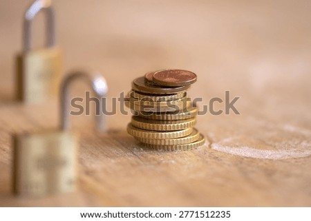 Two open brass padlocks protecting a stack of euro coins on a wooden surface representing wealth protection investment safety and banking security metaphors with selective focus