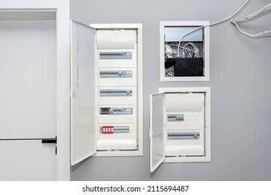 Two Open Electrical Boxes With Fuses And One Multimedia Box, Placed In The Garage In The Gray Wall.