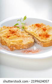 Two Open Sandwiches With Hummus And Paprika Powder On A White Plate 