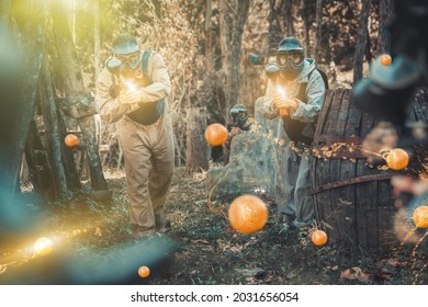 Two opposing teams of players shooting on paintball playing field outdoors, image with lighting and glowing effects