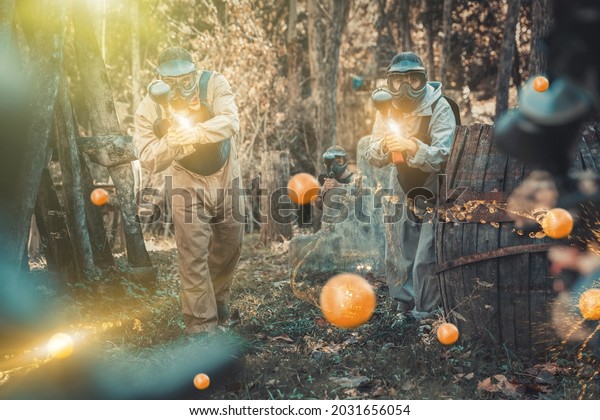 Two\
opposing teams of players shooting on paintball playing field\
outdoors, image with lighting and glowing\
effects