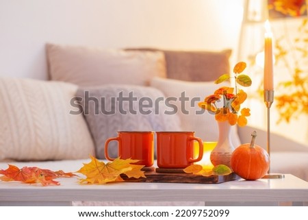 two orange cups with hot drink in autumnal light  interior
