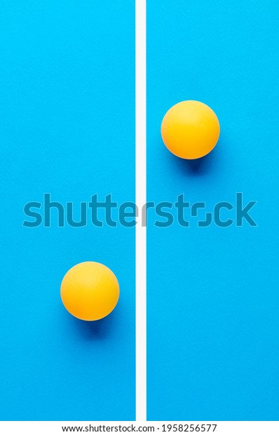 Two\
orange table tennis balls are opposed to each other divided by a\
line on blue background. Competition\
concept.\
\
