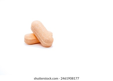 Two orange tablets are placed on top of one another against a plain white background. The tablets have a textured surface and appear to be of a medium size.