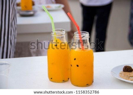 Two original glasses in the form of jars with orange smoothness such as a cocktail or orange juice with trumpets