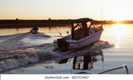 Two Outboard Motor Boats Start On Beautiful Sunset Background In Sunshine, Foam Wake Tracks In Calm Water On Sun On Horizon At Sunny Summer Evening, View From Powerboat, Outdoor Active Recreation