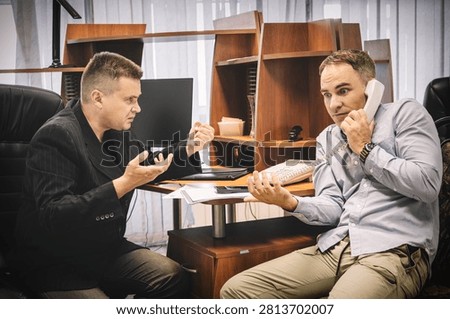 Two outraged men arguing on the phone in office, trying to prove their point, intense negotiation.