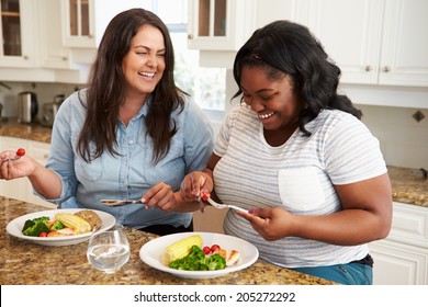 Two Overweight Women On Diet Eating Healthy Meal In Kitchen