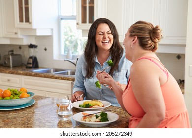 Two Overweight Women On Diet Eating Healthy Meal In Kitchen