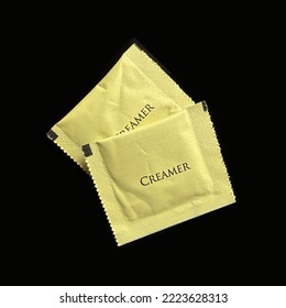 Two Packets Of Dairy Creamer Isolated On A Black Background.