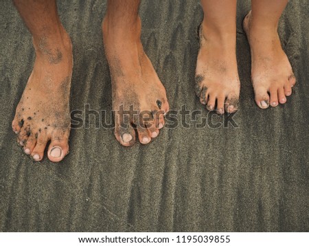 Two pair of feet man and woman standing close on the sand beach, top view