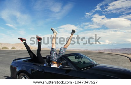 Two pair of legs upside down in a cabriolet car with copy space for the text / Death Valley / USA 