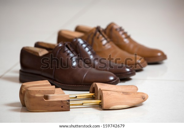 Two pairs of brown\
handmade classic men\'s shoes  with a shoe pads and stretchers\
inside and beside the shoes