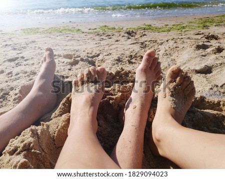 Two pairs of feet on the beach by the sea, selective focus.