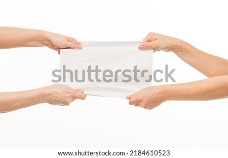 two pairs of female hands hands hold pull in different directions tear a blank sheet of paper document on a white background isolated