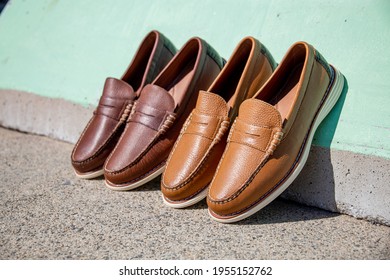 Two pairs of fine genuine leather loafers against a colorful summer color wall.