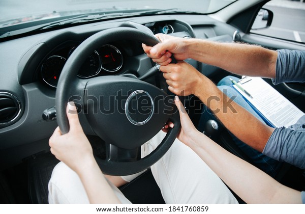 Two pairs\
of hands turn steering wheel together. Female student at driving\
courses hold the wheel and male instructor helps her to drive.\
Driving lessons concept. Close up\
view.