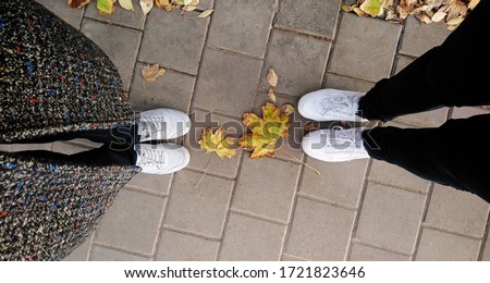 Two pairs of human feet stand on the pavement, keeping a social distance between them. The concept of increasing distance from each other for social distancing to avoid the spread of disease
