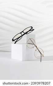 Two pairs of plastic and metallic eyeglass frames on white background. Minimalism, eyewear fashion concept. Trendy eyeglasses still life in minimal style. Optic store discount, sale, promotion.