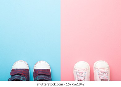 Two pairs of sport shoes for little boys and girls. Pastel blue pink background. Baby footwear. Empty place for text.