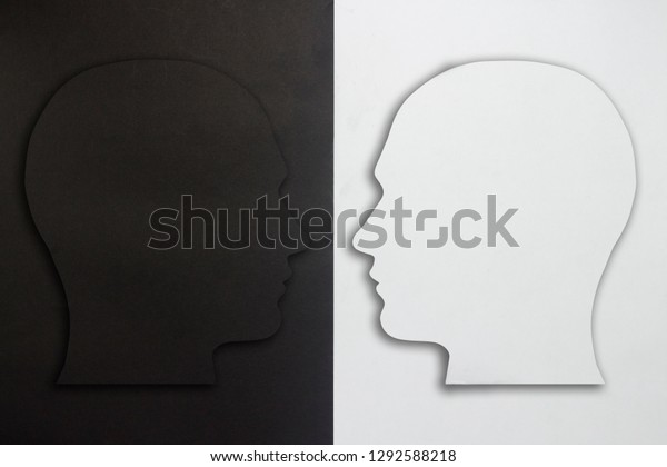 Two paper heads, black and white on a
black and white background. The concept of a split personality,
different opinions, dispute, war. Flat lay, top
view.